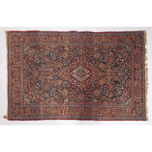 1110 - A Kashan rug, the indigo cartouche field with a central red, ivory and pastel blue lozenge pole meda... 