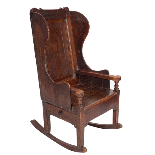 761 - An 18th Century pine and fruitwood lambing armchair, the fielded panel wing back with shaped top rai... 