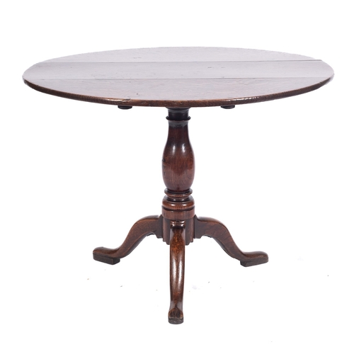 785 - An 18th Century oak circular tea table, with a snap top on baluster turned column and tripod splayed... 