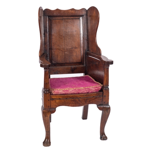 786 - An early 18th Century oak Wainscot armchair, the fielded panel wing back with shaped cresting rail, ... 