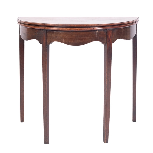 864 - A George III mahogany half round tea table, with a hinged moulded top and shaped apron on square tap... 