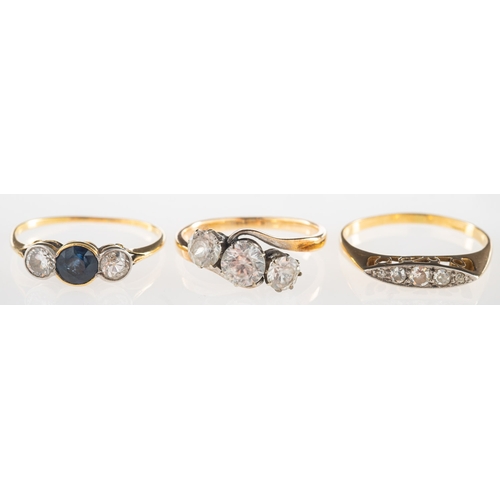 1076 - A group of three rings, including a three stone ring bezel set with a circular-cut sapphire and with... 