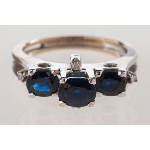 1101 - A late 1970's sapphire and diamond ring, of modernist form and set with three oval-cut sapphires and... 