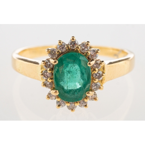 1110 - An emerald and diamond cluster ring, claw set to the centre with an oval-cut emerald, with a surroun... 