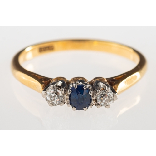 966 - A sapphire and diamond three stone ring, claw set to the centre with an oval-cut sapphire and a bril... 