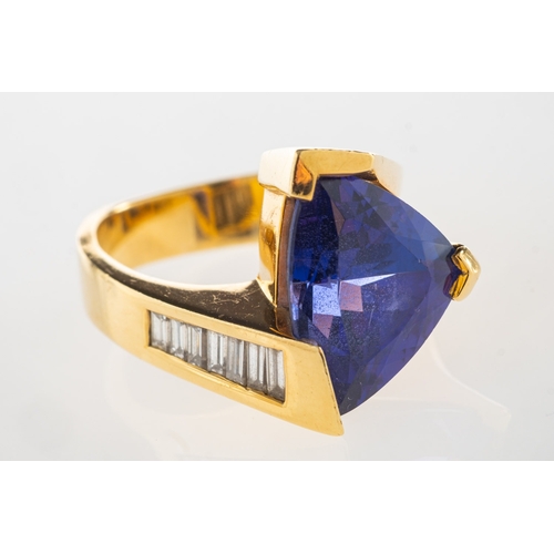 970 - A tanzanite and diamond ring, a modernist designed ring set with a triangular-cut tanzanite and a ro... 