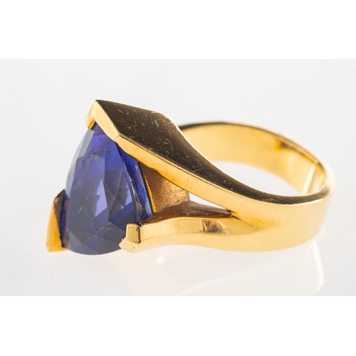 970 - A tanzanite and diamond ring, a modernist designed ring set with a triangular-cut tanzanite and a ro... 