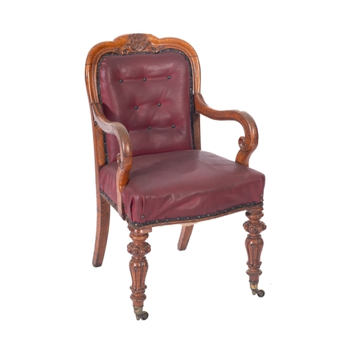 1009 - A Victorian carved oak desk armchair, the upholstered button down cartouche panel back in crimson le... 