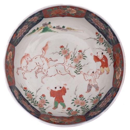 105 - A Japanese Arita porcelain bowl the interior painted with a pair of horses and three boys in a lands... 