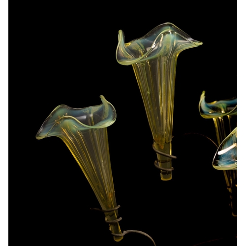 11 - A vaseline glass epergne with seven trumpet shaped glass vases with wavy rims supported on a sinuous... 