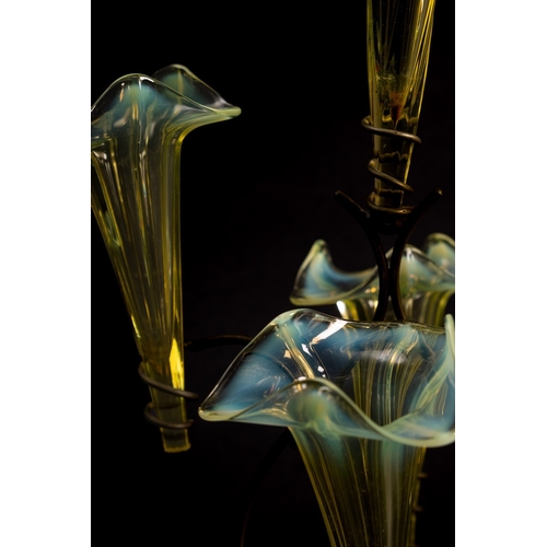 11 - A vaseline glass epergne with seven trumpet shaped glass vases with wavy rims supported on a sinuous... 