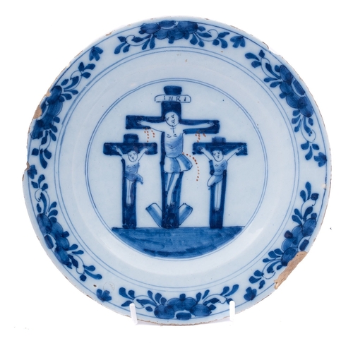 116 - A Dutch delftware crucifixion plate, 18th century painted in blue and iron-red,  the rim with border... 