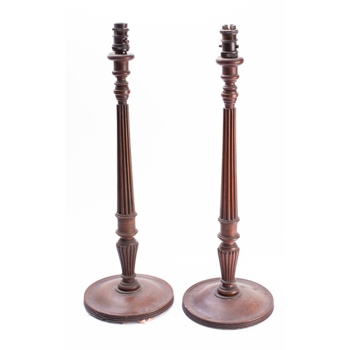 415 - A pair of mahogany table lamps modelled as George III candlesticks, early 20th century; with electri... 