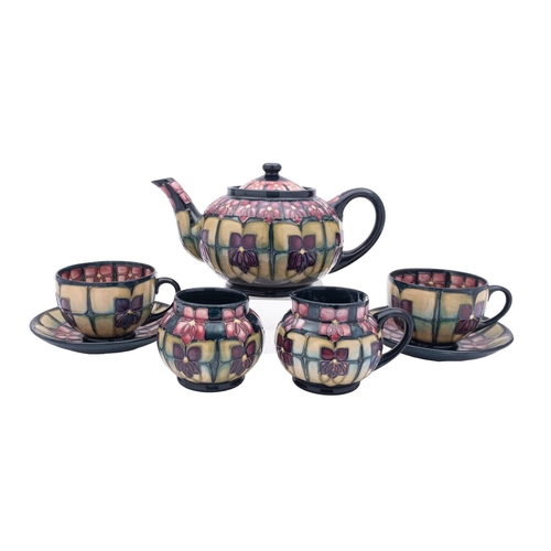 33 - A Moorcroft part tea service in the Violets pattern, comprising a teapot and cover, milk jug [damage... 