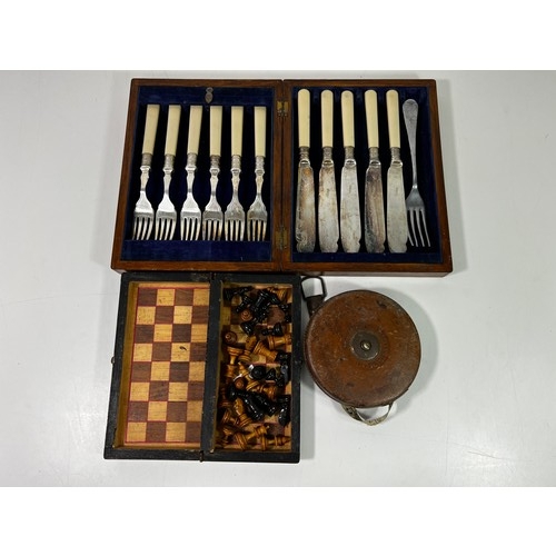 24 - Cased cutlery, antique cased traveling chess set and a tape measure