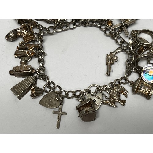 615 - Silver charm bracelet with approx 21 charms - 66.7g gross