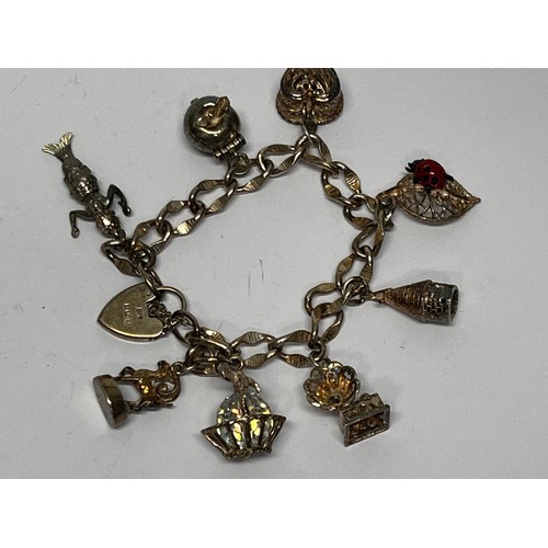 614 - Silver charm bracelet with 8 charms 43.1g gross