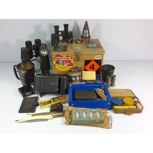 76 - Tin of military items including binoculars, torch etc