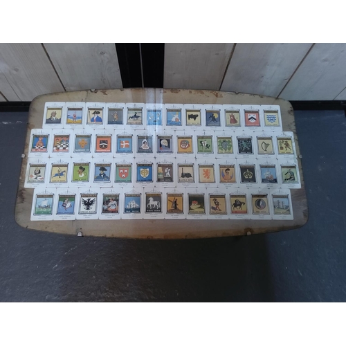 79 - 1950's glass topped coffee table decorated with Whitbread collectors cards, 69 x 40 x 39cms