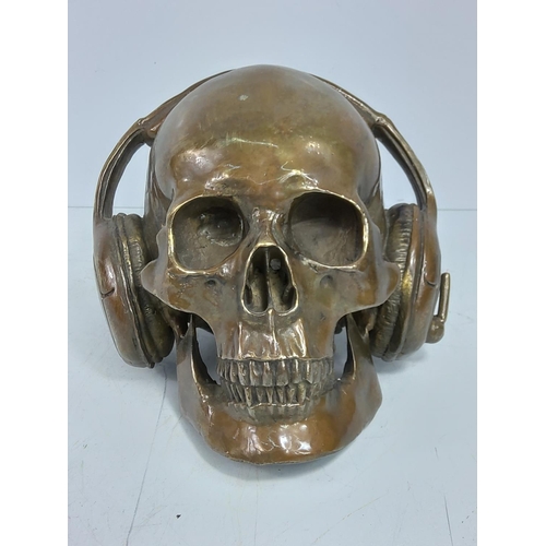 87 - Cast bronze skull with headphones, approx 15cms in height