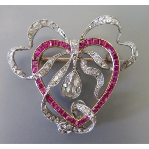 163 - A Ruby and Diamond Heart and Ribbon Brooch in a precious white and yellow metal setting, 40mm drop x... 