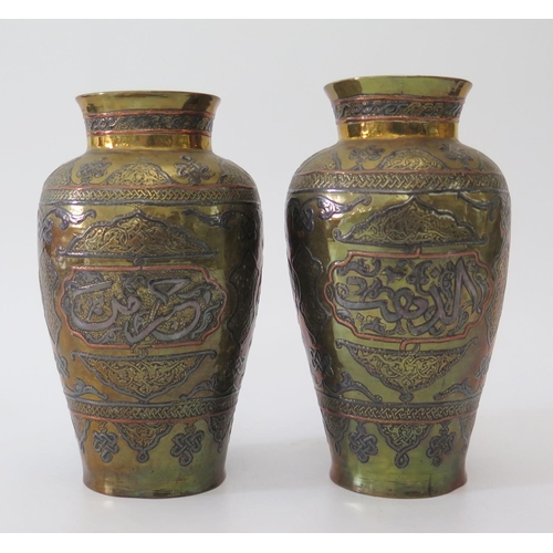 543 - A pair of small Islamic brass vases with silver and copper inlay