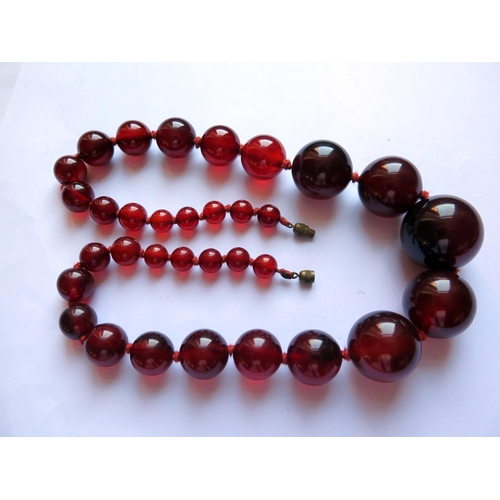 624 - A Graduated Faux Cherry Amber Bead Necklace, 55cm, 109g, largest bead 28.5mm