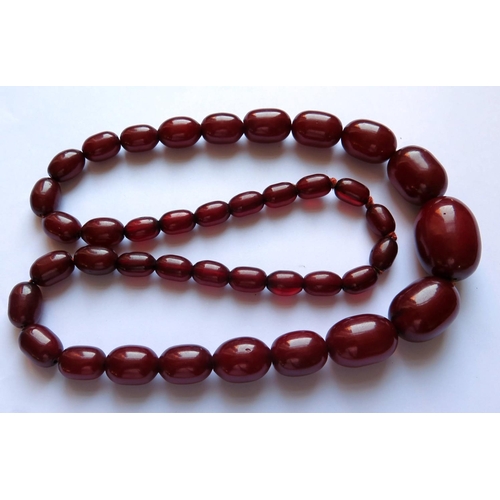 629 - A Graduated Faux Opaque Cherry Amber Bead Necklace, c. 74cm long, 97g, largest bead 33x24mm