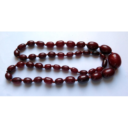 630 - A Graduated Faux Opaque Cherry Amber Bead Necklace, c. 89cm long, 92.6g, largest bead 35x24mm