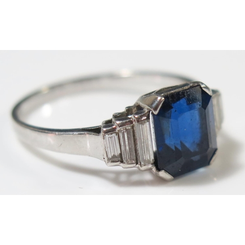 506A - An Art Deco Emerald Cut Sapphire Ring with baguette cut diamond shoulders in an unmarked white metal... 