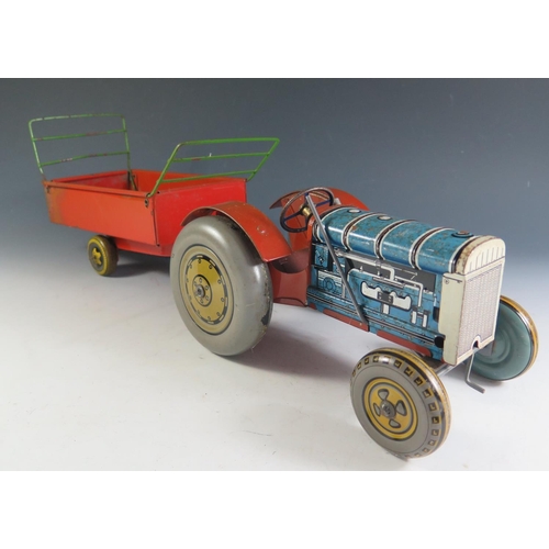 76 - A Large Mettoy Clockwork Tinplate Tractor in blue and red and trailer (tractor measures 23cm approx)... 