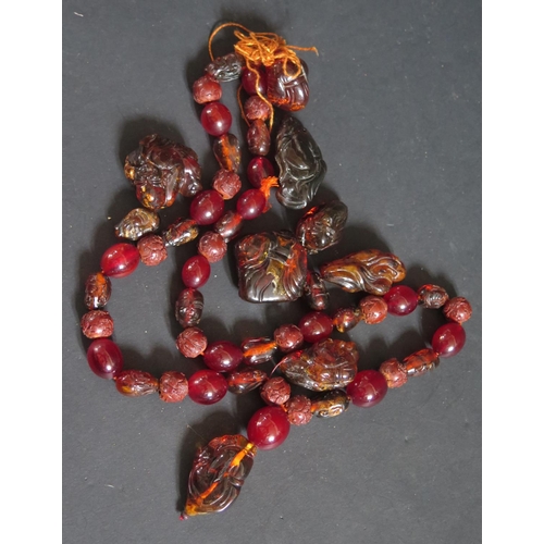 156 - A Carved Amber Necklace (thread broken), carved amber beads and two small carved amber figures, 158.... 