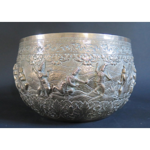 982 - A Large Burmese Silver Thabeik Bowl decorated figures in various poses with foliate scroll borders a... 