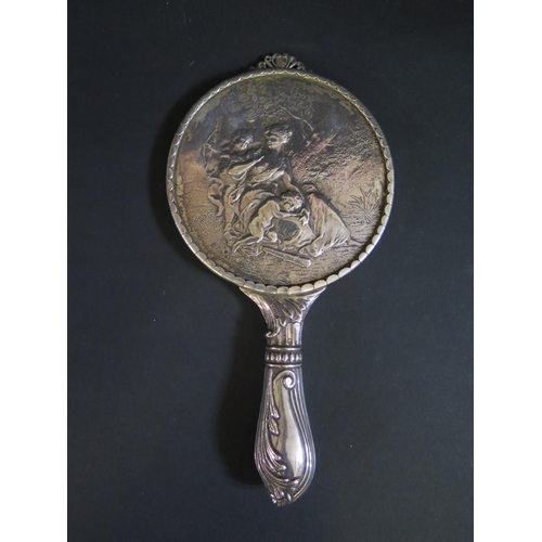 1081 - A Victorian Silver Backed Hand Mirror decorated with a scene of a seated woman with putti in a woode... 