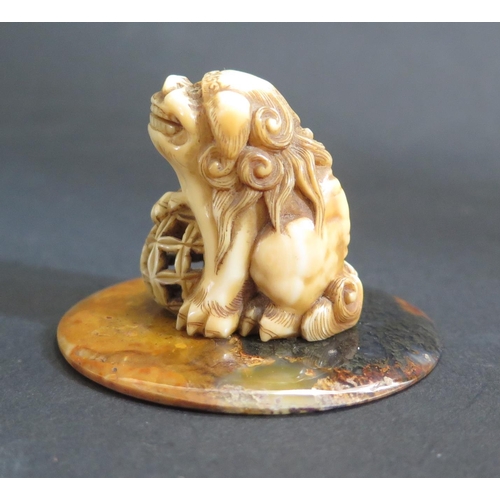 1183 - An Antique Chinese Carved Ivory Foo Dog on a polished agate base, 38mm high