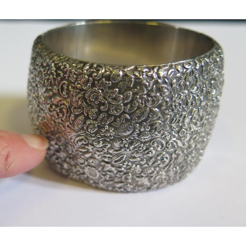 39 - A Victorian Silver Hinged Bangle embossed with floral decoration, 49mm wide, two dents to body, 99g