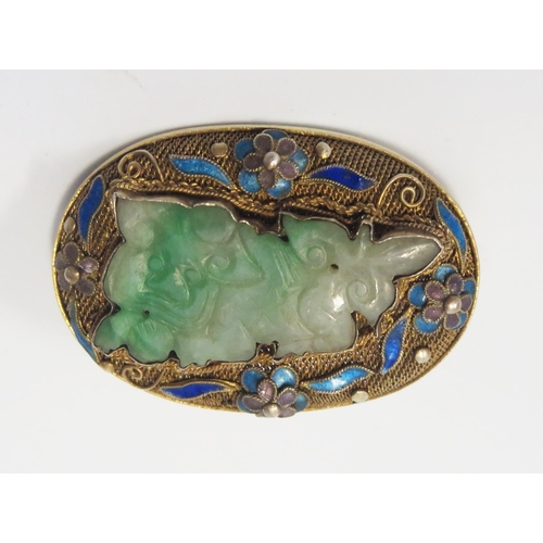 1898 - A Chinese Carved Jadeite Brooch in a silver gilt and enamel setting, 42x29mm