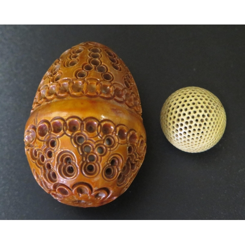 544 - An Egg Shaped Carved and Pierced Nut with screw opening and containing a pierced ball, 6cm