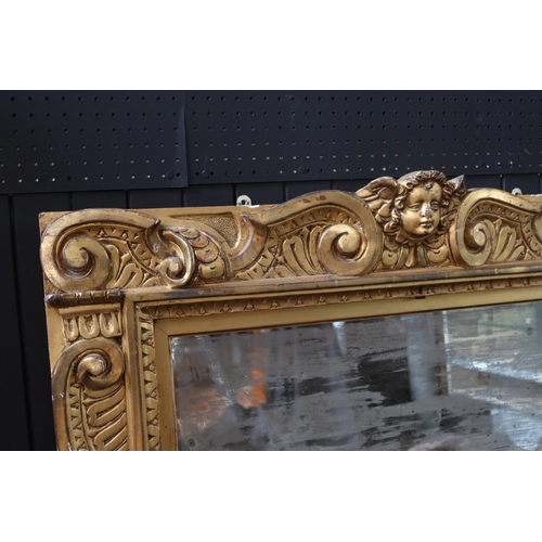 274 - An Early 19th Century Gilt Gesso Framed Mirror with scrolling foliate decoration and Cupid mask to t... 