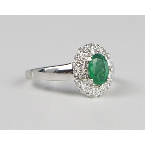 302b - A 14K White Gold, Emerald and Diamond Oval Cluster Ring, the central 7 x 5 mm stone surrounded by 10... 