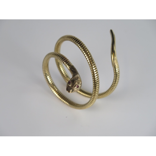 321 - A Victorian Style 9ct Gold Spring Fit Snake Bangle with chased decoration and ruby eyes to the head,... 