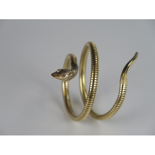 321 - A Victorian Style 9ct Gold Spring Fit Snake Bangle with chased decoration and ruby eyes to the head,... 