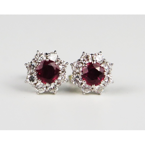 335 - A Pair of Ruby and Diamond Cluster Stud Earrings, the central c. 5.2mm stones surrounded by eight c.... 