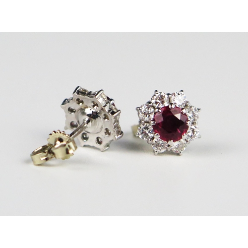 335 - A Pair of Ruby and Diamond Cluster Stud Earrings, the central c. 5.2mm stones surrounded by eight c.... 