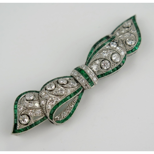 235 - A Belle Epoque Platinum, Emerald and Diamond Millegrain Set Bow Brooch, the principal 3mm diamonds w... 