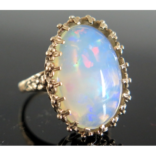 136 - 9ct Gold and White Opal Dress Ring, the c. 21.5x14.5mm singlet stone with a deep range of green, blu... 