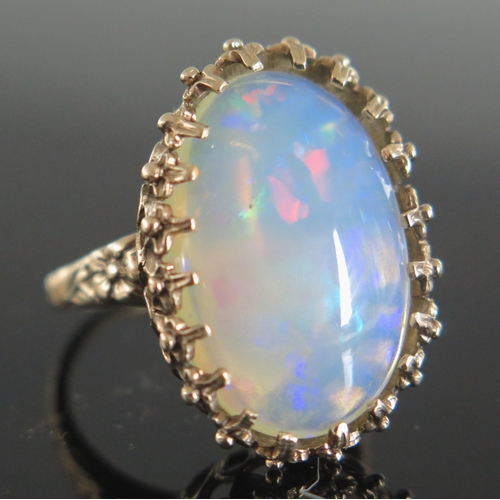 136 - 9ct Gold and White Opal Dress Ring, the c. 21.5x14.5mm singlet stone with a deep range of green, blu... 