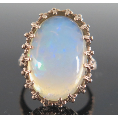 136 - 9ct Gold and White Opal Dress Ring, the c. 21.5x14.5mm singlet stone with a deep range of green, blu... 