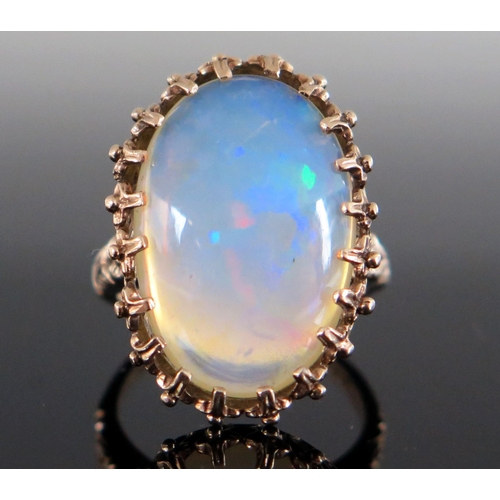 136 - 9ct Gold and White Opal Dress Ring, the c. 21.5x14.5mm singlet stone with a deep range of green, blu... 