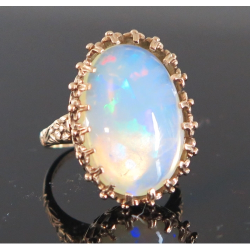 136 - 9ct Gold and White Opal Dress Ring, the c. 21.5x14.5mm singlet stone with a deep range of green, blu... 